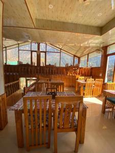 ein Restaurant mit Holztischen und -stühlen und Fenstern in der Unterkunft SAIRRA - Hotel & Restaurant in Manali