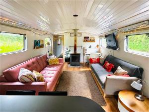 a living room with couches and a tv in a trailer at Boutique Boat Stays in Bath