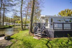 a house with a deck next to a river at Stunning Lodge Boasting Lake Views At Weely Bridge Holiday Park Ref 69005l in Weeley