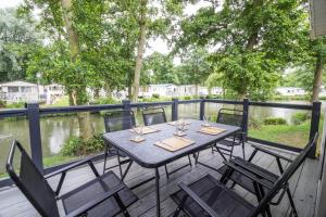 a table and chairs on a deck next to a river at Stunning Lodge Boasting Lake Views At Weely Bridge Holiday Park Ref 69005l in Weeley
