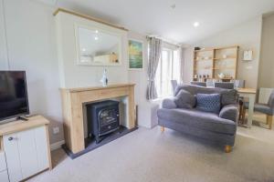 a living room with a fireplace and a chair and a television at Stunning Lodge Boasting Lake Views At Weely Bridge Holiday Park Ref 69005l in Weeley