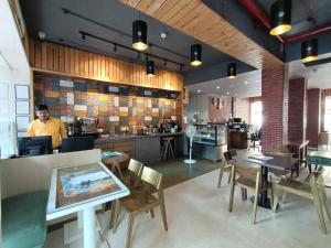 a man standing in a restaurant with tables and chairs at Hotel Highway Inn Andheri East in Mumbai