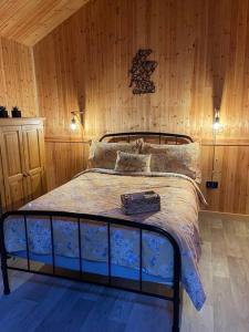 1 dormitorio con 1 cama con pared de madera en Taigh Beag en Inverlochy