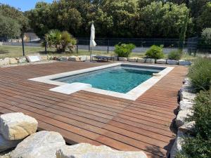 una piscina en una terraza de madera con suelo de madera en Mas Provençale au calme Piscine, en Vacqueyras