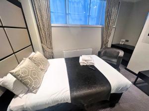 a bedroom with a bed with a window and a chair at Great St Helen Hotel in London