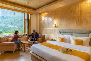 two people sitting in a hotel room with a large bed at ArtBuzz Manali in Manāli