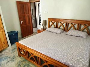 a bed in a bedroom with a wooden frame at Tulivu House -2bedroom vacation home close to the beach in Dar es Salaam