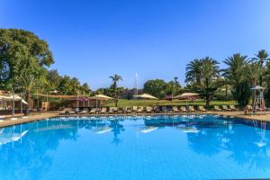 a large swimming pool with chairs and umbrellas at Barceló Palmeraie in Marrakesh