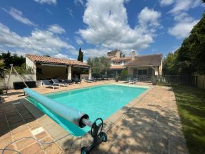 a swimming pool with a pool noodle in front of a house at Les Hauts de Beillard in Merville