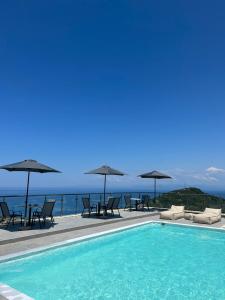 a swimming pool with chairs and umbrellas and the ocean at MELIKIRON LUXURY APARTMENTS in Agios Nikitas