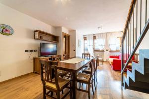 a dining room with a table and chairs and a television at Appartamento Dolomiti Alleghe in Alleghe