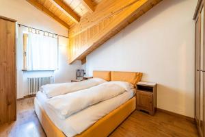 two beds in a room with a wooden ceiling at Appartamento Dolomiti Alleghe in Alleghe