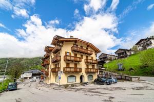 a yellow building with cars parked in a parking lot at Appartamento Dolomiti Alleghe in Alleghe