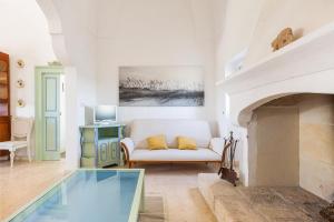 ein Wohnzimmer mit einer weißen Couch und einem Kamin in der Unterkunft Masseria Pepe by BarbarHouse in Torre Ovo
