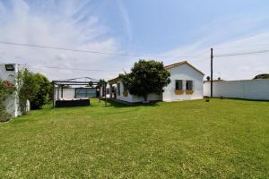 een tuin met een wit huis en een groen gazon bij Chalet La Alberca in Chiclana de la Frontera