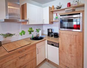 a kitchen with white cabinets and a sink and a microwave at Haus Meeresblick - Ferienwohnung Strandnah A 1.07 (Ref. 128675) in Baabe