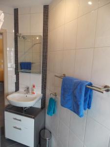 y baño con lavabo y ducha con toallas azules. en Ferienwohnung Sarah & Thorsten Blum en Kelberg