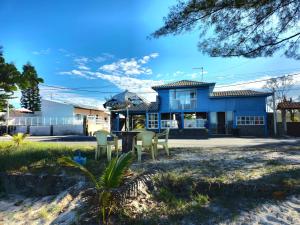 a blue house with chairs in front of it at Pousada Viva Mar in Saquarema