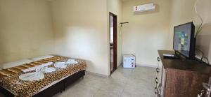 a room with a bed and a tv and a room with a leopard print at Pousada Viva Mar in Saquarema