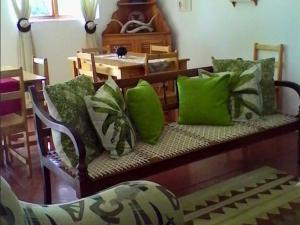 a couch with green pillows on it with a table at Joalani Guest Farm in Murraysburg