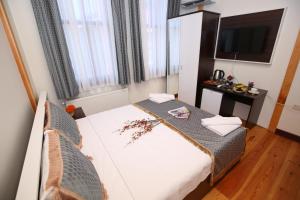 um pequeno quarto com uma cama e uma televisão em Grand almira hotel em Istambul