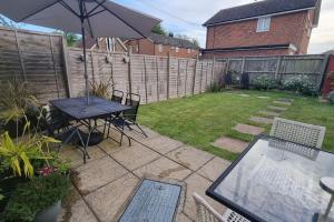 a patio with a table and an umbrella in a backyard at Entire House With Garden & Parking Nr Ashford Int in Ashford