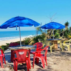 a table with chairs and blue umbrellas on the beach at Pousada Viva Mar in Saquarema