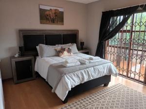 a bedroom with a large bed and a large window at Majestic View Self Catering Guest House in Sabie