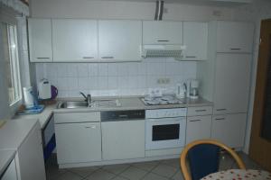 een kleine keuken met witte kasten en een wastafel bij Ferienwohnung Zum Schwalbennest in Eimke