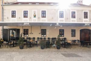 um restaurante com mesas e cadeiras em frente a um edifício em Sobe Merlon em Osijek