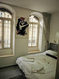 a bedroom with a bed and two windows at Beautiful apartment in the center ofJerusalem 4 in Jerusalem