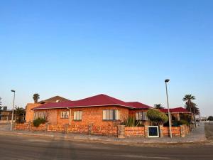 a brick house with a red roof on a street at Seaview Family Cottage in Swakopmund