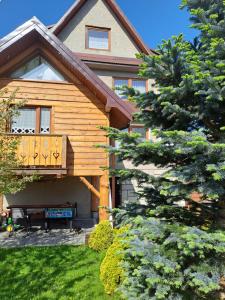 a house with a deck and a bench in the yard at Majkowiczówka in Czorsztyn