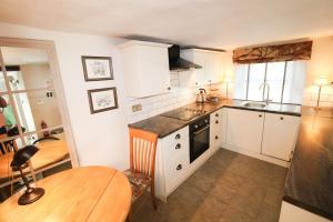 kuchnia z białymi szafkami, stołem i jadalnią w obiekcie Kirkstone Cottage ideal for a romantic break centrally located in Ambleside w mieście Ambleside
