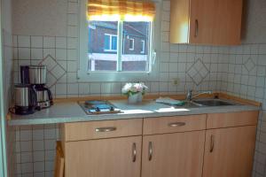 encimera de cocina con fregadero y ventana en das Fischerhus, en Bensersiel