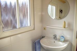 a white bathroom with a sink and a mirror at das Fischerhus in Bensersiel