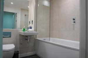 a bathroom with a tub and a sink and a toilet at Luxury Townhouse In Central Manchester in Manchester