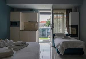 a room with two beds and a kitchen with a window at Edem Luxury Apartments in Nea Peramos