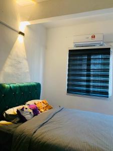 - une chambre avec un lit doté d'une tête de lit verte et d'une fenêtre dans l'établissement Homestay Dizaherbs KT, à Kuala Terengganu