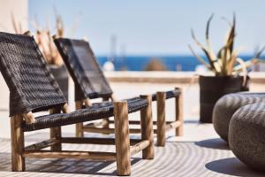 três cadeiras de madeira sentadas num pátio com a praia em Serenity Suite Milos em Mandrakia