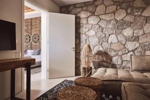 a living room with a couch and a stone wall at Serenity Suite Milos in Mandrakia
