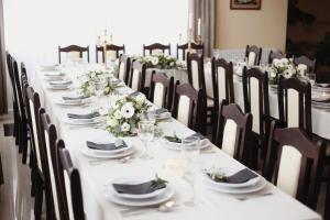 a long table with chairs and plates and flowers at Arkánum Hotel in Balatonmáriafürdő