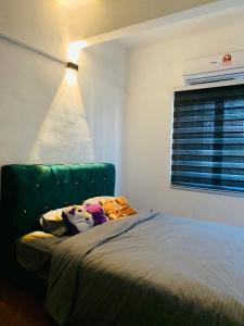 1 dormitorio con 1 cama con cabecero verde y ventana en Homestay Dizaherbs KT, en Kuala Terengganu