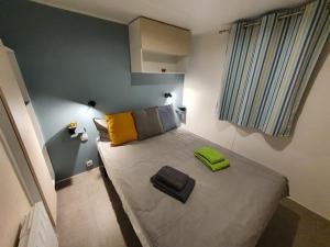 een kleine slaapkamer met een bed met gele en grijze kussens bij Campingland Ostsee - Mobilheim 77Steinküste in Schashagen
