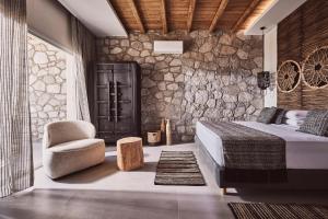 a bedroom with a bed and a stone wall at Serenity Suite Milos in Mandrakia