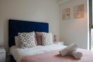a bedroom with a bed with a blue headboard at Luxury Townhouse In Central Manchester in Manchester