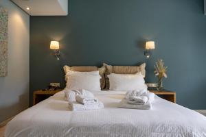 a bedroom with a large white bed with towels on it at Edem Luxury Apartments in Nea Peramos
