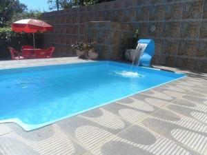 a swimming pool with a fountain in a backyard at Pousada Viva Mar in Saquarema