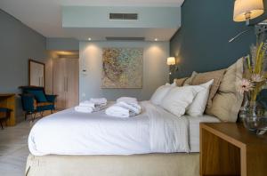ein Schlafzimmer mit einem großen weißen Bett mit Handtüchern darauf in der Unterkunft Edem Luxury Apartments in Néa Péramos