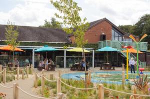 a pool with umbrellas and people sitting outside a building at Appletree Holiday Park in Boston